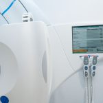 Equipamento moderno de radioterapia com painel de controle e tela em uma sala clínica hospitalar.