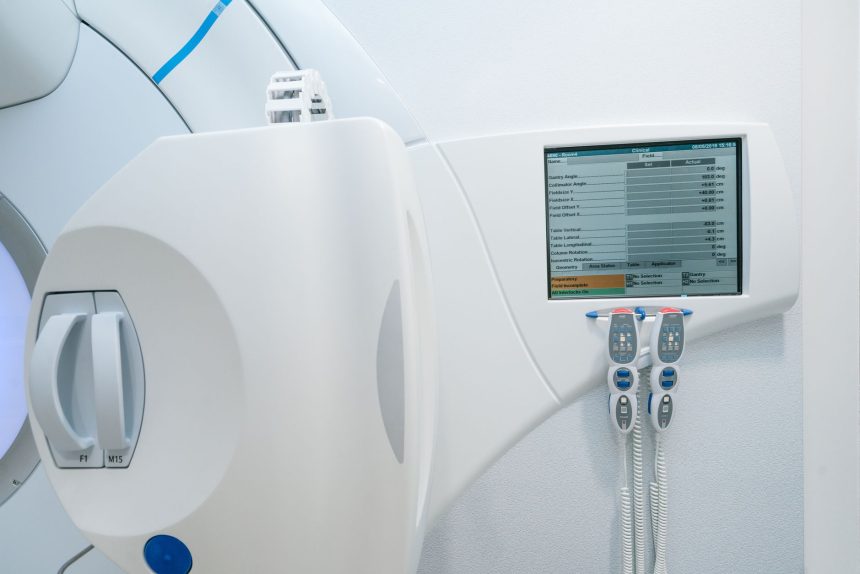 Equipamento moderno de radioterapia com painel de controle e tela em uma sala clínica hospitalar.